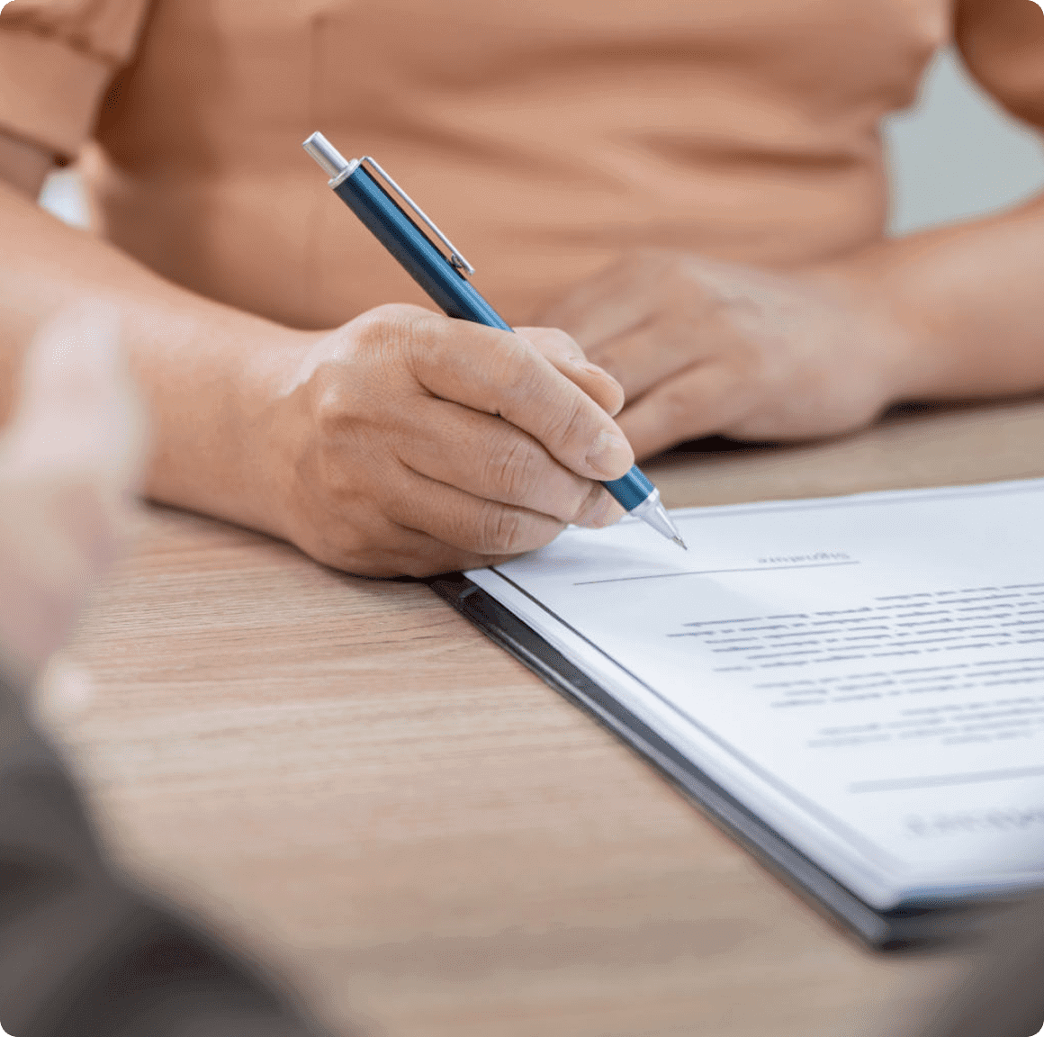 Person signing a document with pen.
