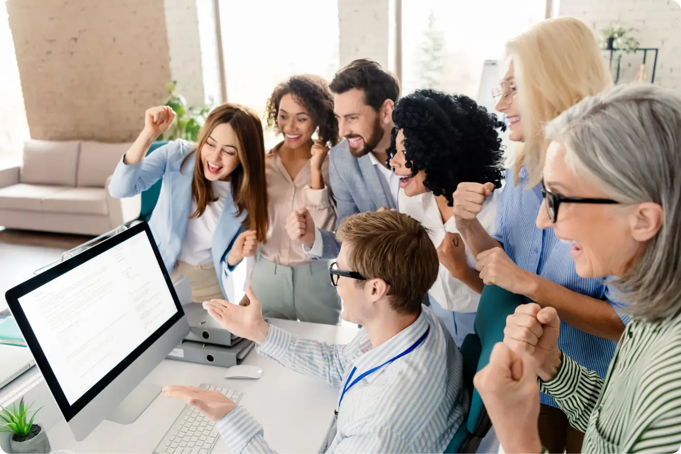 Team celebrating success at computer screen.